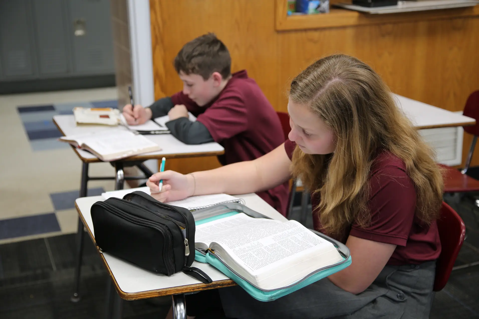 Students studying their Bibles at their desks