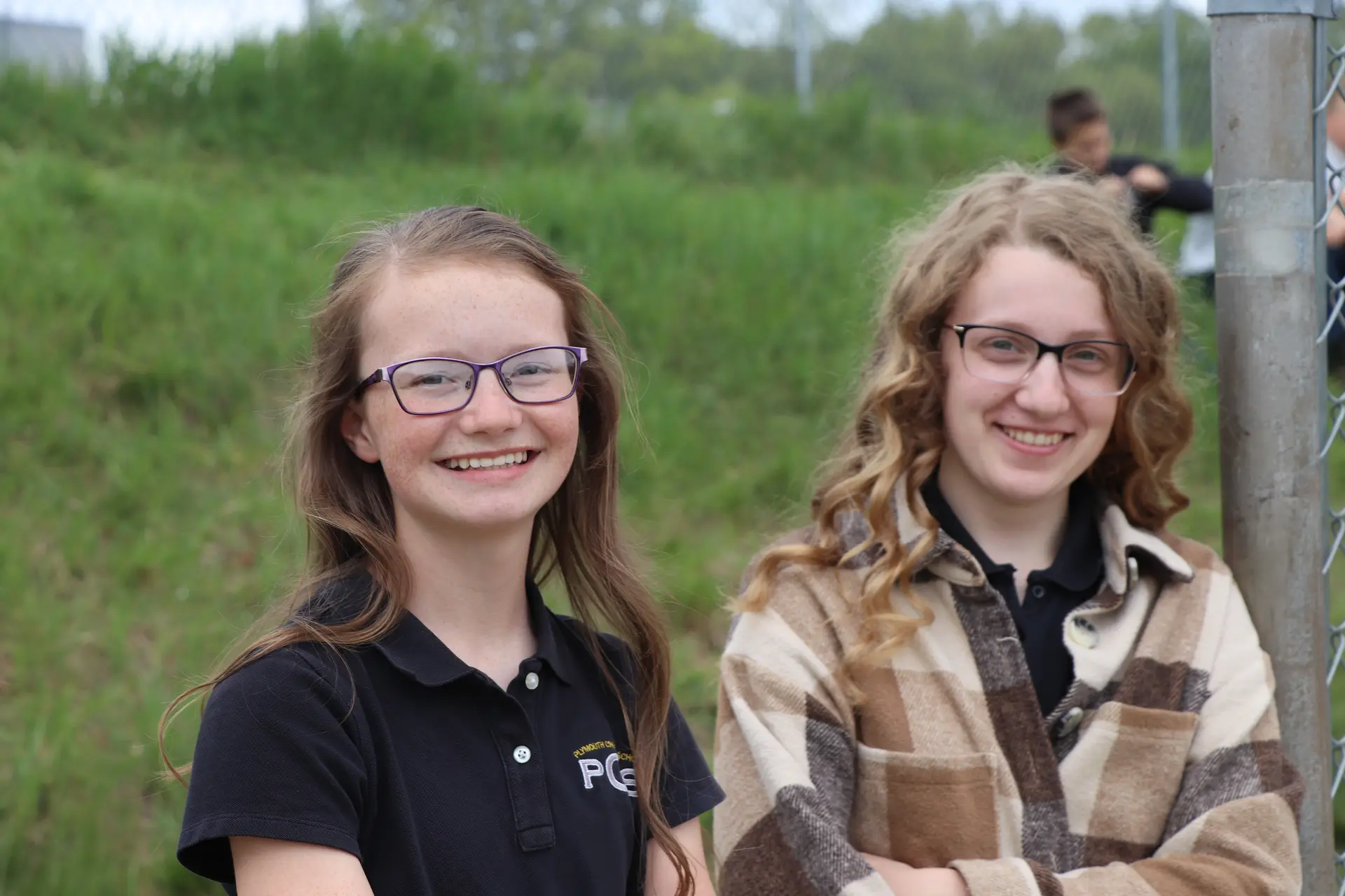 Two smiling students outdoors on a sunny day