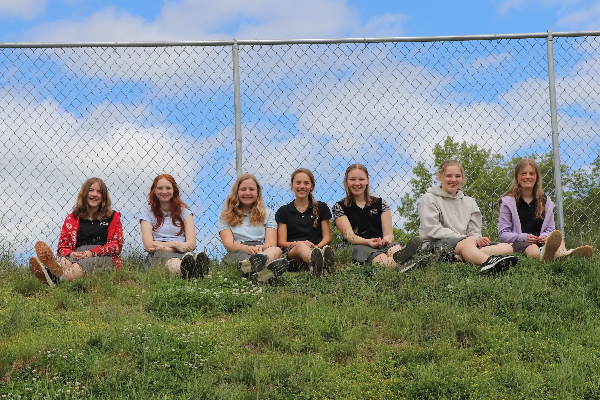 Students sitting together on a grassy hill