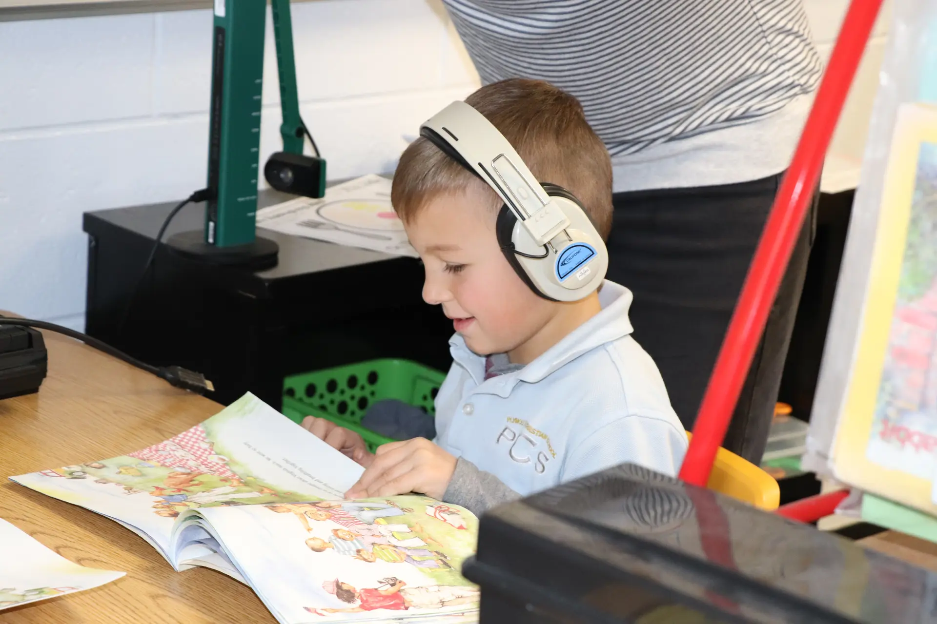 A young student in headphones reading a picture book