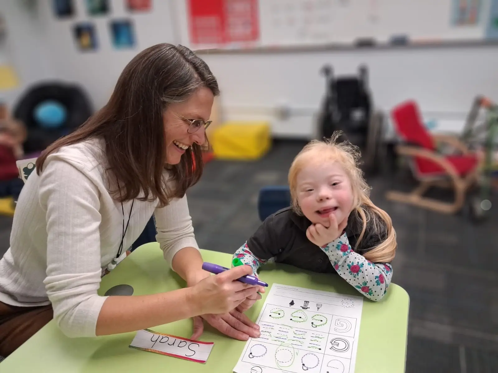 A teacher and a smiling student working on a worksheet together