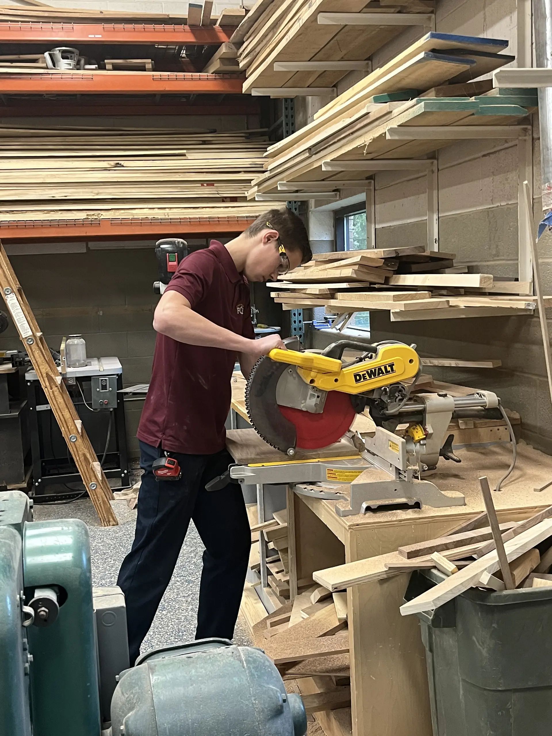 A student cutting wood with a miter saw in shop class